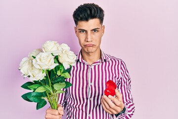 Sticker - Young hispanic man holding bouquet of flowers and wedding ring depressed and worry for distress, crying angry and afraid. sad expression.