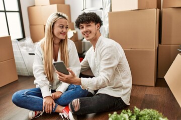 Poster - Young beautiful couple smiling happy using smartphone at new home.