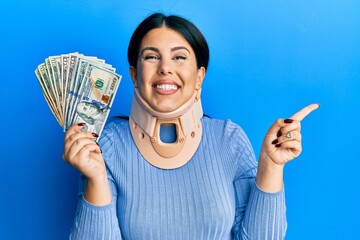 Poster - Beautiful brunette woman wearing cervical collar holding insurance money smiling happy pointing with hand and finger to the side