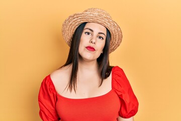 Sticker - Young hispanic woman wearing summer hat relaxed with serious expression on face. simple and natural looking at the camera.