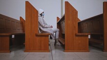 Young Caucasian Female Wearing Hygiene Face Mask While Praying In Empty Church	