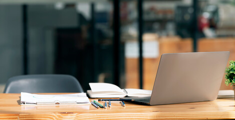 Laptop computer with opened lid on table in modern office room. Creative workspace background concept.