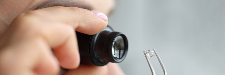 Woman looks through magnifying glass at precious stone