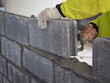 Bricklayer worker installing brick masonry on exterior wall with trowel putty knife. closeup photo, blurred.