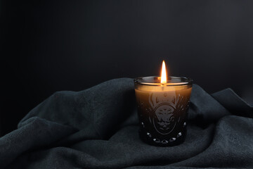 Wall Mural - the burning luxury aromatic scent candle glass is on the black table decorated with black cloth in the living room to creat relax and romantic ambient during valentine dinner