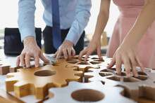 Business People Making Whole Picture Of Wooden Gears On Workplace Together In Office