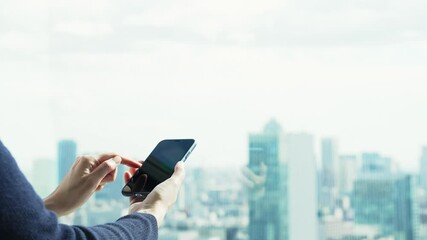 Poster - 都市を背景にスマートフォンを使う女性
