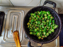 Stock Photo Of Fresh Green Cut Lady Fingers Or Okra Pisces Cooking In The Small Iron Indian Style Cauldron Or Kadhai, Wooden Spoon Kept On Gas Stove In The Kitchen Under Artificial Light At Bangalore