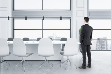 Aufkleber - Businessman standing in modern white concrete meeting room interior with panoramic city view, furniture and daylight.