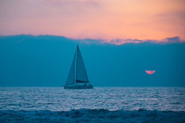  Yacht sailing in the sunrise time. Sea landscape view with a beautiful sailboat. Yachting tourism sea voyage on the sail boat. Romantic trip on the sail vessel.