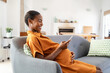 © Rido - Pregnant african woman using smartphone at home