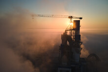 Aerial View Of Cement Factory With High Concrete Plant Structure And Tower Crane At Industrial Production Site On Foggy Morning. Manufacture And Global Industry Concept