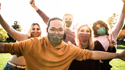 Group of young people wearing face masks having fun outdoors - New normal lifestyle concept with friends looking at camera - People lifestyle and healthcare medicine