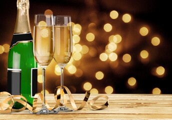 Canvas Print - Glasses and bottle of champagne with serpentine streamers against lights on background.