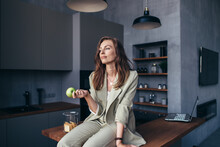 Woman Sits In The Kitchen With An Apple During A Break
