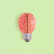 © jbuinac - Minimal abstract surreal conceptual composition made of bulb and model of human brain isolated on vibrant light green background. Brainstorm creative symbol. Flat lay.