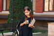 © standret - With smartphone in hands. Schoolgirl is outside near school building