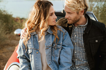 Wall Mural - White couple hugging while standing by car during trip