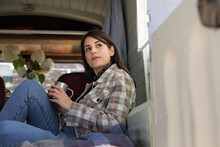 Female Drinking Coffee In Campervan On Road Trip Holiday