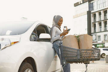 African muslim woman chraging car and use phone