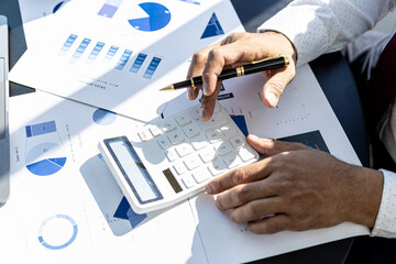 Wall Mural - Business man using a calculator to calculate numbers on a company's financial documents, he is analyzing historical financial data to plan how to grow the company. Financial concept.