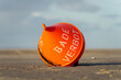 orange buoy at the beach of Sankt Peter Ording, german text 