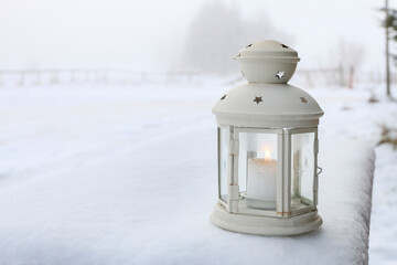 Canvas Print - An iron lantern with candle on the wooden fence in the garden, in winter.