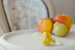Nibbler with fresh apples and pear on light kids table, closeup. Baby feeder