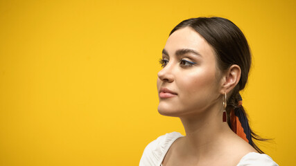 Wall Mural - Portrait of young brunette woman looking away isolated on yellow.