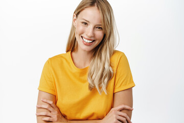Wall Mural - Portrit of beautiful modern woman with natural blond hair, white smile, clear perfect skin, laughing and smiling, standing in yellow t-shirt over white background