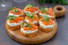 Smoked Salmon Bruschetta With Cream Cheese, Cucumber And Dill Served On Round Wooden Board. Close Up, Selective Focus.
