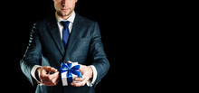 Holding Gift Box. Happy Young Business Man Holding Surprise Giftbox Present With Blue Ribbon Isolated On Black Background. Present For Birthday, Valentine Day, Christmas, New Year.