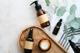 Set of natural organic SPA beauty products on wooden board with eucalyptus leaves. Amber glass cosmetic bottles top view.