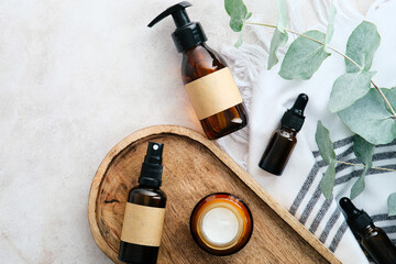 Wall Mural - Set of natural organic SPA beauty products on wooden board with eucalyptus leaves. Amber glass cosmetic bottles top view.