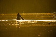 Scenic View Of Fisherman In Canoe At Sunrise On The River