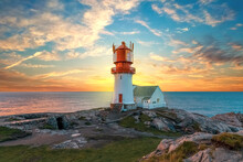 Lighthouse Surrounded By Rocks At Sunset, Lighthouse Surrounded By Rocks Near The Ocean
