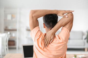 Wall Mural - Young man stretching his spine at home