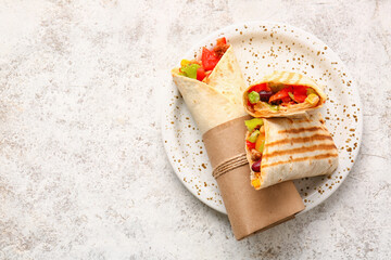 Wall Mural - Plate of tasty Mexican burritos with vegetables on light background
