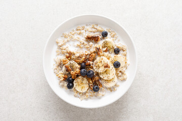 Wall Mural - Oatmeal bowl. Oat porridge with banana, blueberry, walnut, chia seeds and almond milk for healthy breakfast or lunch. Healthy food, diet. Top view.