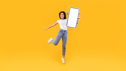 Poster - Happy woman showing white empty smartphone screen and jumping