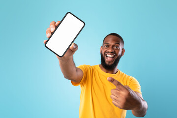 Poster - New awesome mobile app. Black guy pointing at smartphone with blank screen on blue background, mockup