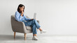 © Prostock-studio - Serious young woman looking at laptop screen, sitting in armchair, having problem with online work or studies