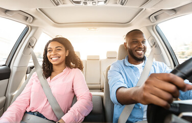 Happy black couple enjoying long drive on luxury car