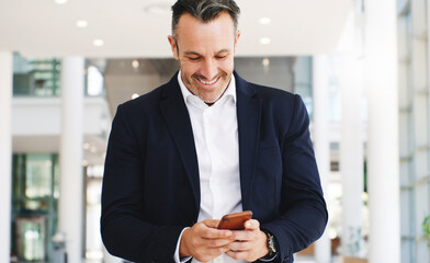 Aufkleber - Instant connection brings instant good news. Shot of a mature businessman using a smartphone while walking through a modern office.