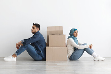 Wall Mural - Upset arab family sitting separated by paper boxes on floor