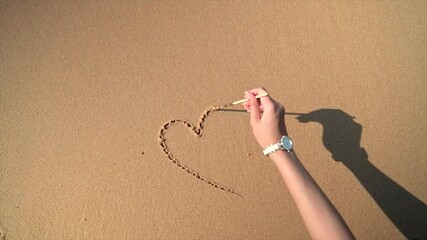 Wall Mural - woman drawing heart in the sand