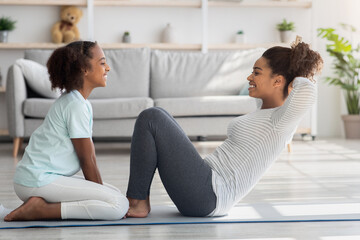 Wall Mural - Joyful black mother and kid in sportswear training together