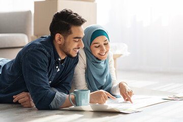 Creative muslim family laying on floor with apartment scheme