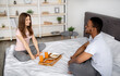 © Prostock-studio - Young black guy and his girlfriend having breakfast on bed at home