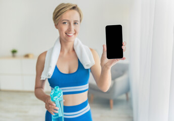 Happy sporty woman showing cell phone with blank screen